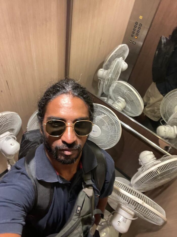 A selfie in sunglasses before a pile of electric fans