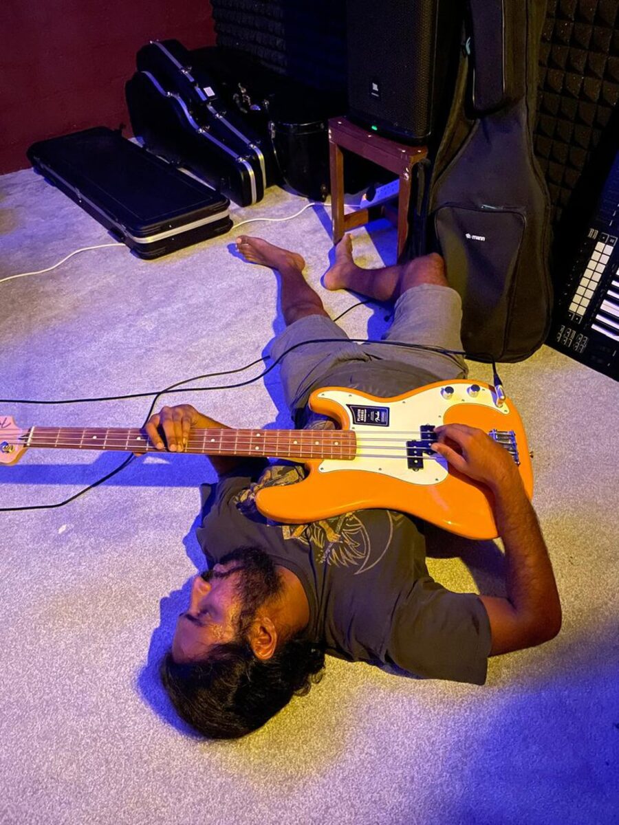 Lying on the studio floor playing a bass guitar under violet light